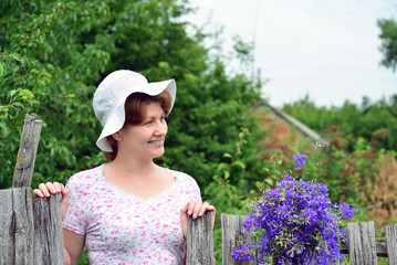 Woman with   wildflowers near  wooden fence in the village