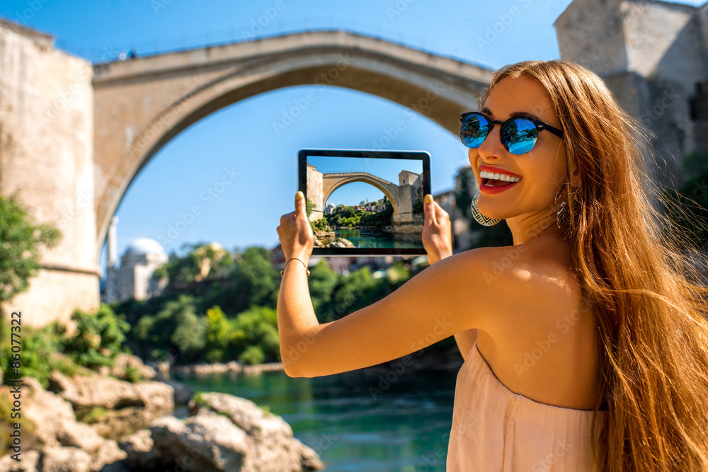 Woman photographing old bridge in Mostar city - obrazy, fototapety, plakaty 