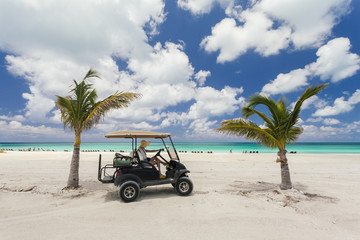 Image of woman riding a golf cart on the beach.