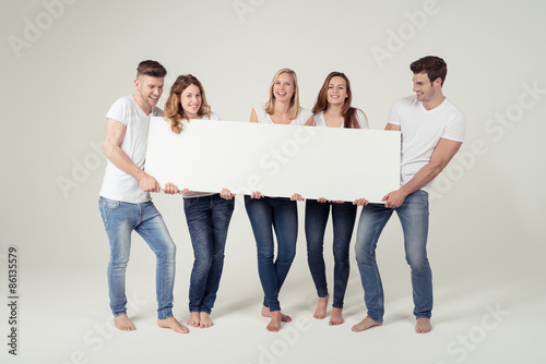 Fotografia lachende junge leute zeigen ein schild