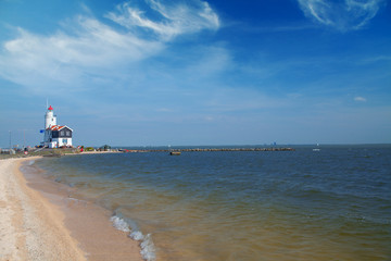 Wall Mural - lonely lighthouse stands on the spit in the sea near the village