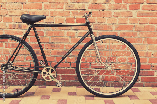 Naklejka na drzwi Old style singlespeed bicycle against brick wall, tinted photo