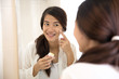 © Odua Images - Happy asian woman putting make-up on, smiling at mirror