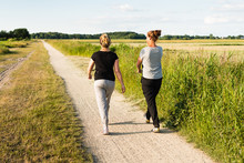 Two Women Walking On Sandy Path