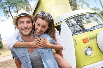 Wall Mural - Cheerful couple standing in front of camper van