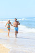 © goodluz - Couple having fun running on the beach