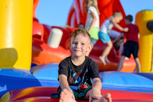 Smiling Little Boy Sitting On A Jumping Castle