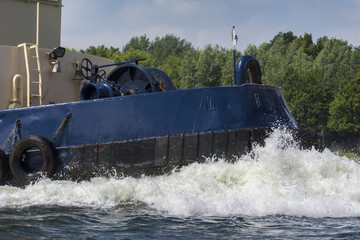 Bow of a tugboat sailing true the water. Big wave in front.