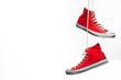 Red sneakers hanging in front of a white background