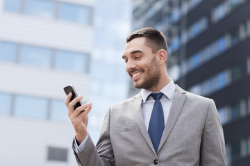 Wall Mural - smiling businessman with smartphone outdoors