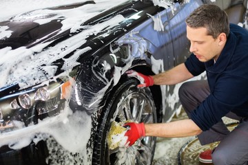 Poster - Man worker washing car's alloy wheels on a car wash