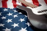Fototapeta Miasta - Vintage Bass guitar body on american flag background. selective focus image with shallow depth of field