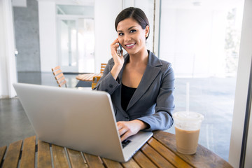 executive finance real estate agent at a coffee shop working on a laptop and talking on the cell pho