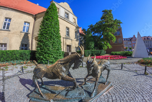 Plakat Poznań- rzeźba na placu Kolegiackim przedstawiająca koziołki będące symbolem miasta