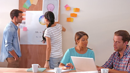 Sticker - Creative team using laptop computer while their colleagues looking at color sample