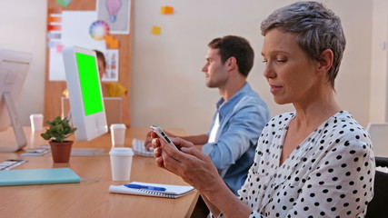 Sticker - Casual businesswoman texting while her colleagues working on laptop