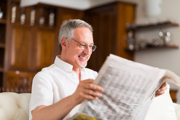 Wall Mural - Mature man reading a newspaper