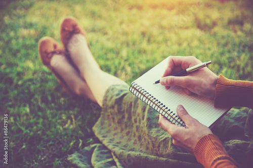 Fotografía female hands with pen writing on notebook on grass outside