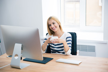 Poster - Happy female designer drinking coffee in office