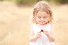 Cute Baby Girl 2-3 Year Old Holding Flower In Meadow Outdoors. Childhood. Playful.