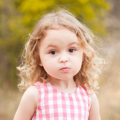 Wall Mural - Baby girl 2-3 year old looking at camera over nature background outdoors. Childhood. 