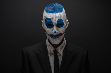 Wall Mural - Terrible clown and Halloween theme: Crazy blue clown in black suit isolated on a dark background in the studio