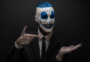 Wall Mural - Terrible clown and Halloween theme: Crazy blue clown in black suit isolated on a dark background in the studio