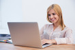 © Drobot Dean - Smiling businesswoman using laptop in office