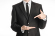 © Alex - Businessman and gesture topic: a man in a black suit with a tie shows the left hand index finger on his right hand on a white isolated background in studio