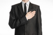 Businessman and gesture topic: a man in a black suit with a tie put his hand on his chest isolated on white background in studio