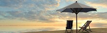 Deck Chairs And Umbrella In Sunset On The Beach