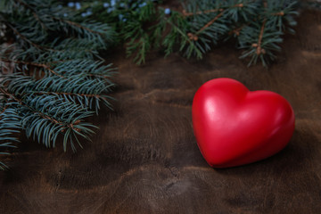 Christmas composition with heart and fir branches on wooden back