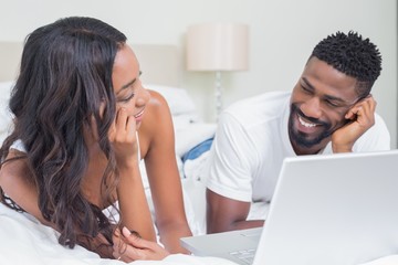 Wall Mural - Relaxed couple using laptop on bed