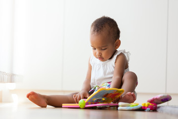 Wall Mural - Portrait of little African American little girl sitting on the f