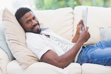 Wall Mural - Man using his tablet on couch