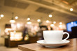 A White cup on wooden table with blur background coffee shop - vintage filter