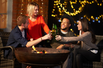 Group Of Friends Enjoying Evening Drinks By Firepit