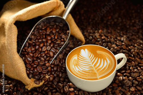 Fototapeta na wymiar Cup of coffee latte and coffee beans on wooden table