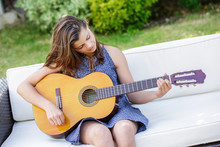 Portrait Of Very Cute Teenager Playing Guitar In Her Garden