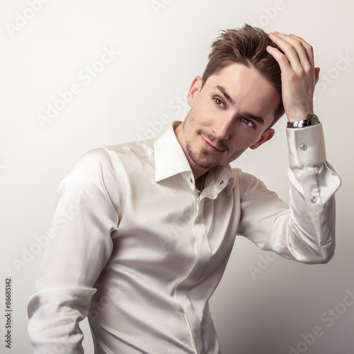 Fototapeta na wymiar Elegant young handsome man in white silk shirt. Studio fashion portrait.
