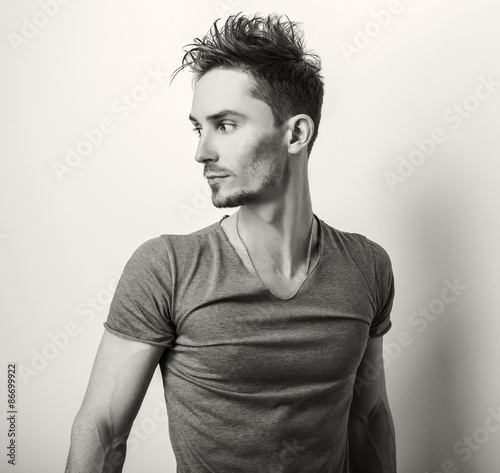 Fototapeta na wymiar Portrait of young handsome man in grey t-shirt. Sepia studio photo.
