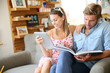 © goodluz - Trendy couple in coffee shop reading magazine sitting in sofa