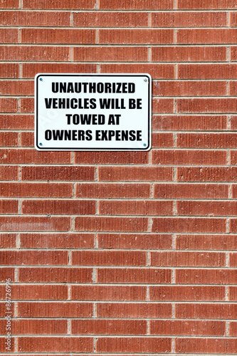 Fotografie, Obraz Vertical composition of a sign warning that unauthorized vehicles will be towed