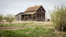 Horizontal Image Of An Old Abandoned Wood Board House With A Little Lean To Added On Under A Blue Sky In The Summer Time