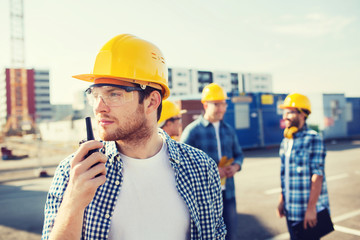 Canvas Print - group of builders in hardhats with radio