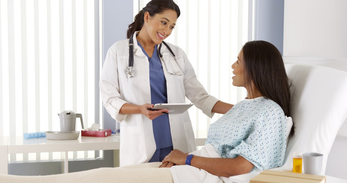 Wall Mural -  - Hispanic female doctor talking to African patient