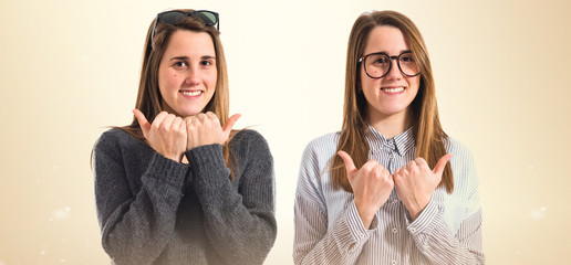 Twin sisters with thumbs up