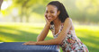 © Mark Adams - Black woman sitting on a park bench smiling