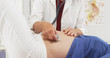 © rocketclips - Senior doctor checking pregnant woman's belly