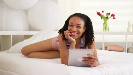 Wall Mural - Black woman smiling with tablet on bed